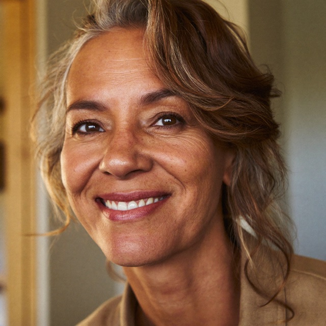 Denise sorrindo, em casa, com luz natural
